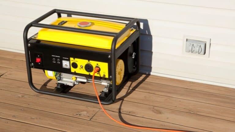 Yellow generator on wooden deck with orange cord plugged in, running toward an exterior outlet, ready for use.