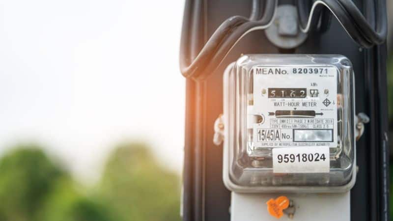 Close-up of an outdoor electricity meter showing numbers and labels, set against a blurred green background.