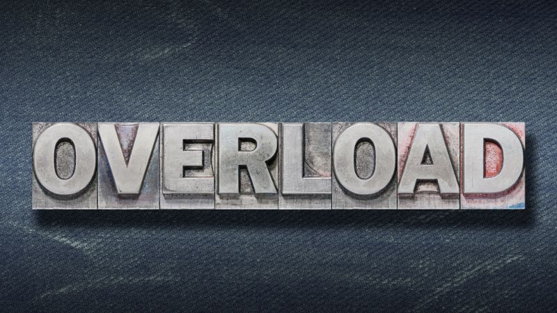 Overload word spelled with metallic type blocks on dark textured background.