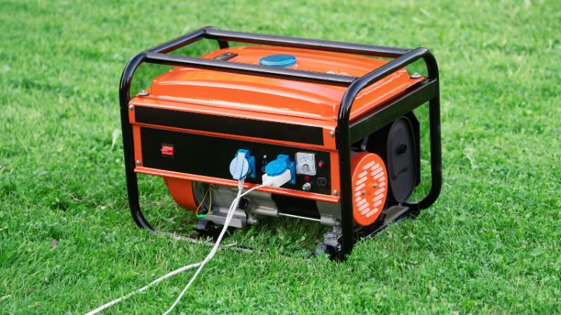 Portable orange generator on green grass for outdoor power backup and camping needs.
