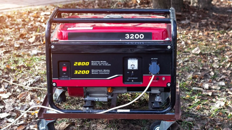 Portable generator with red and black design, featuring power outlets and control panel, ideal for backup power during outages or outdoor activities.