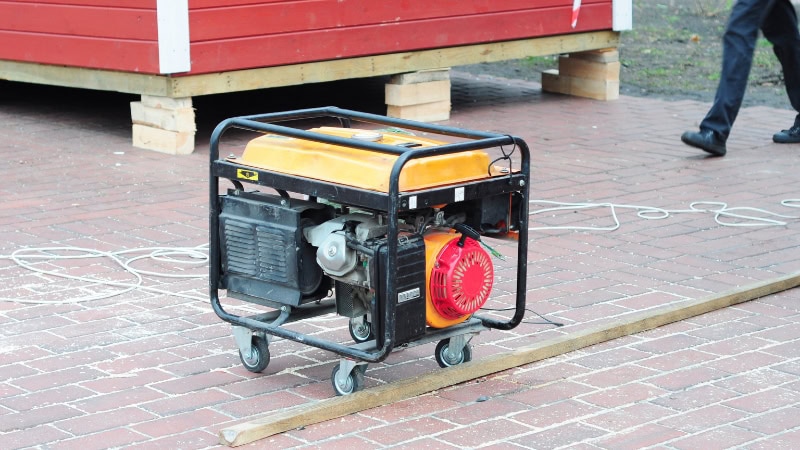 Compact portable generator on brick pavement, ideal for emergency power supply during outages, featuring a sturdy frame and wheels for easy transport.