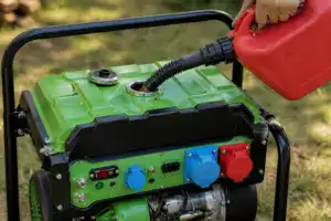 A person refueling a portable green generator with a red fuel container outdoors, showing the fuel hose connected to the generator's tank.
